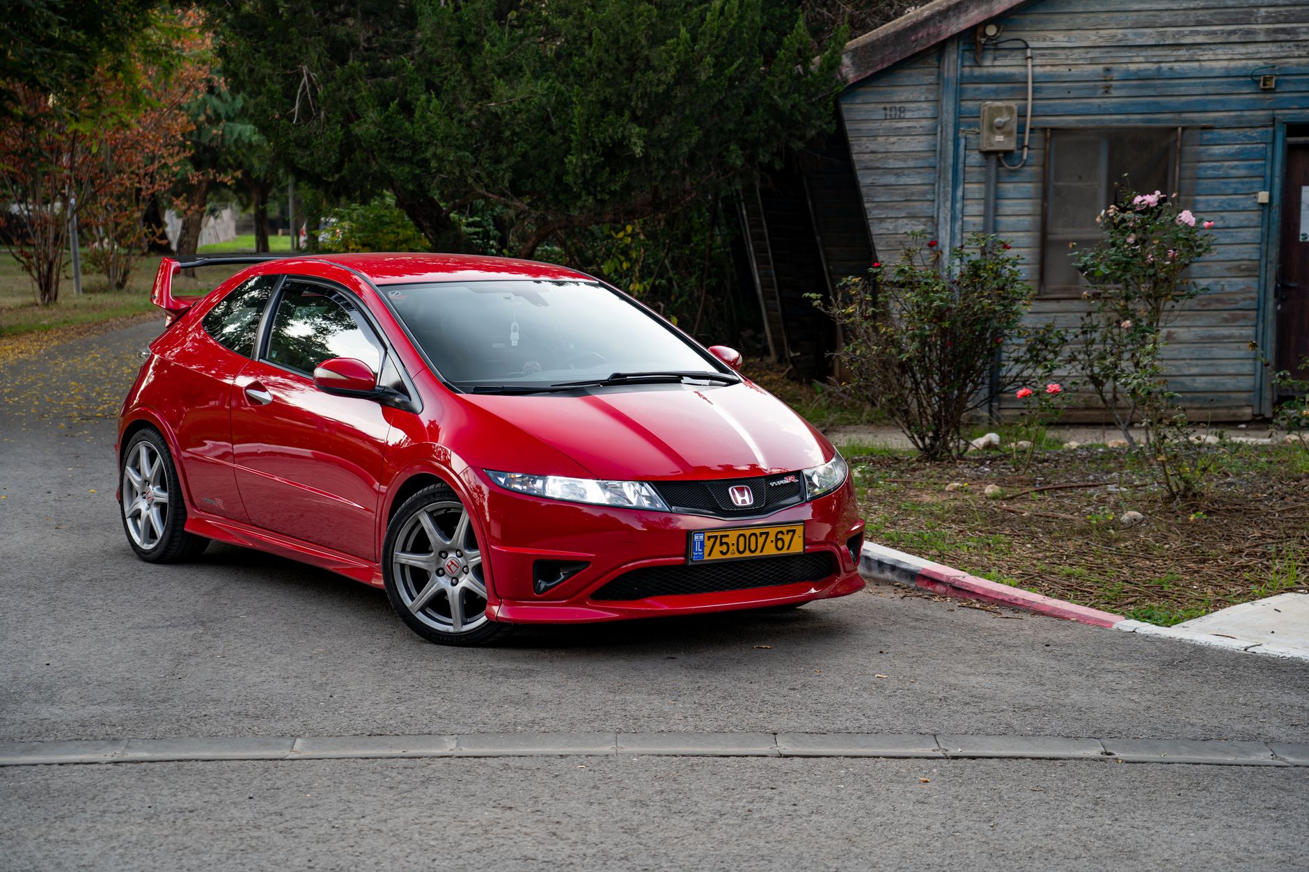 Red Honda Civic Type R parked outdoors, featuring a sleek design and vibrant color.
