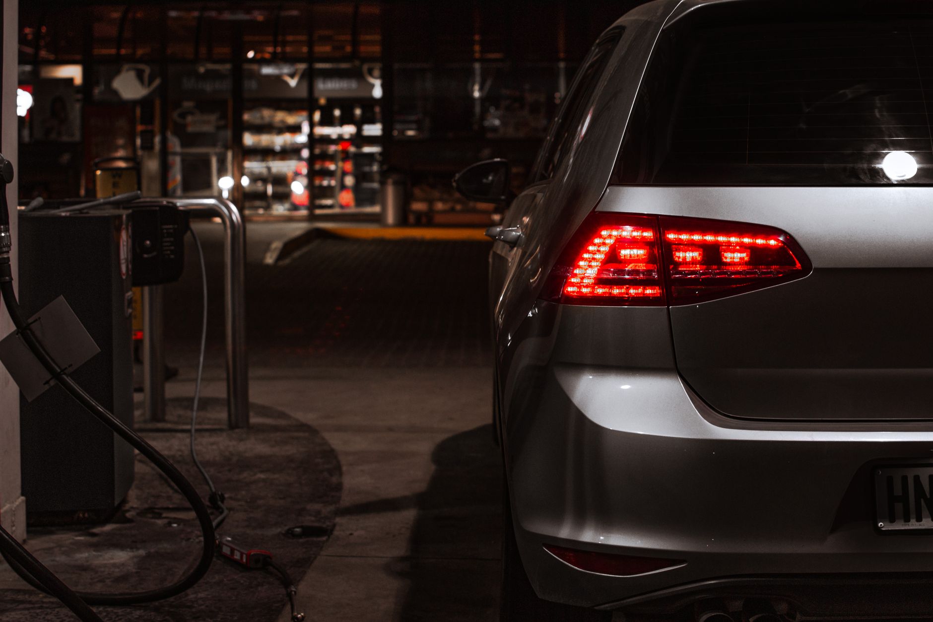 A sleek car at a gas station illuminated by night lights, conveying modern elegance and transportation.