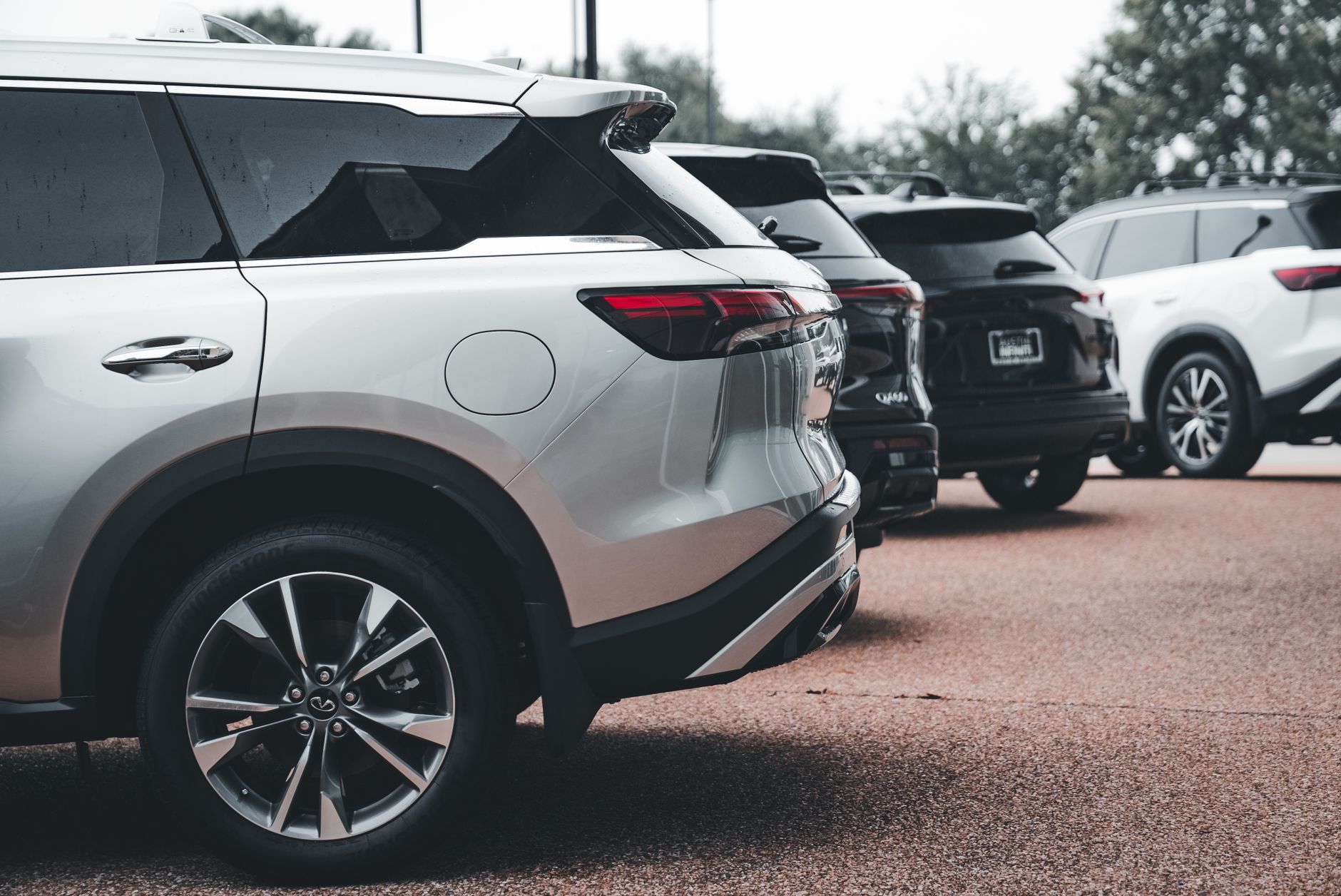 A row of parked SUVs including a silver Infiniti QX60 in an outdoor setting.
