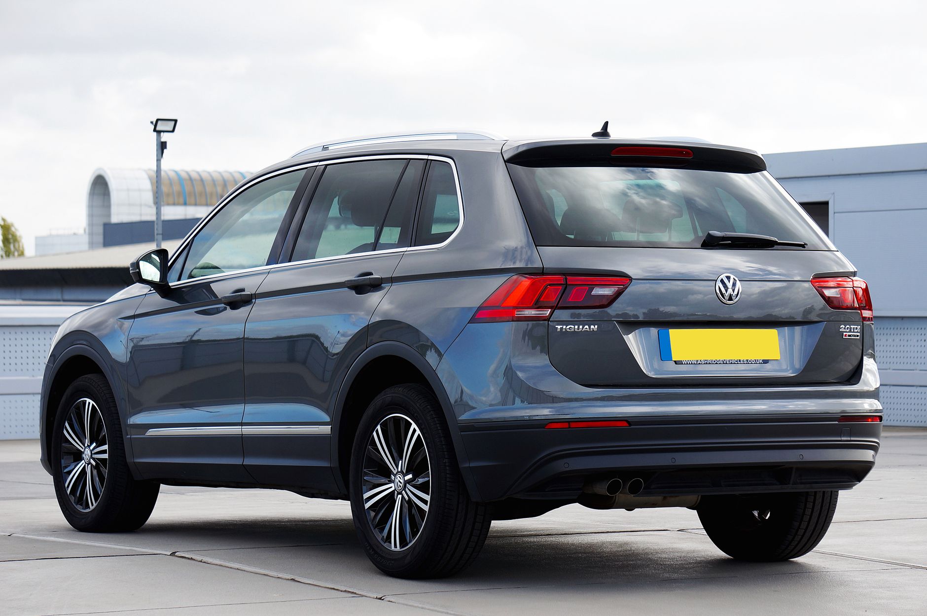 Rear view of a gray Volkswagen Tiguan SUV parked in an urban setting, showcasing modern design.