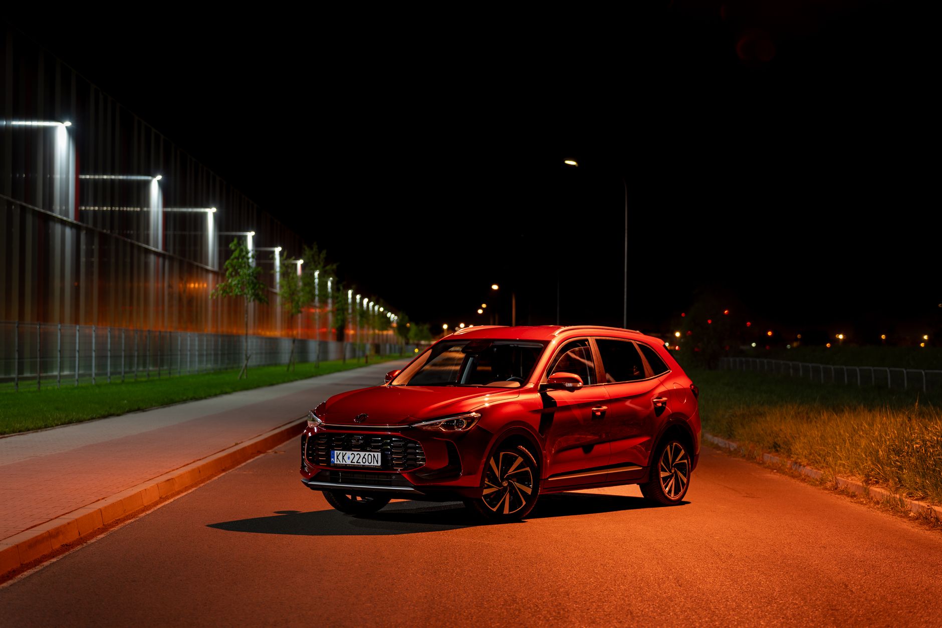 Red SUV illuminated by streetlights at night in Kokotów, Poland. Modern urban vibe.