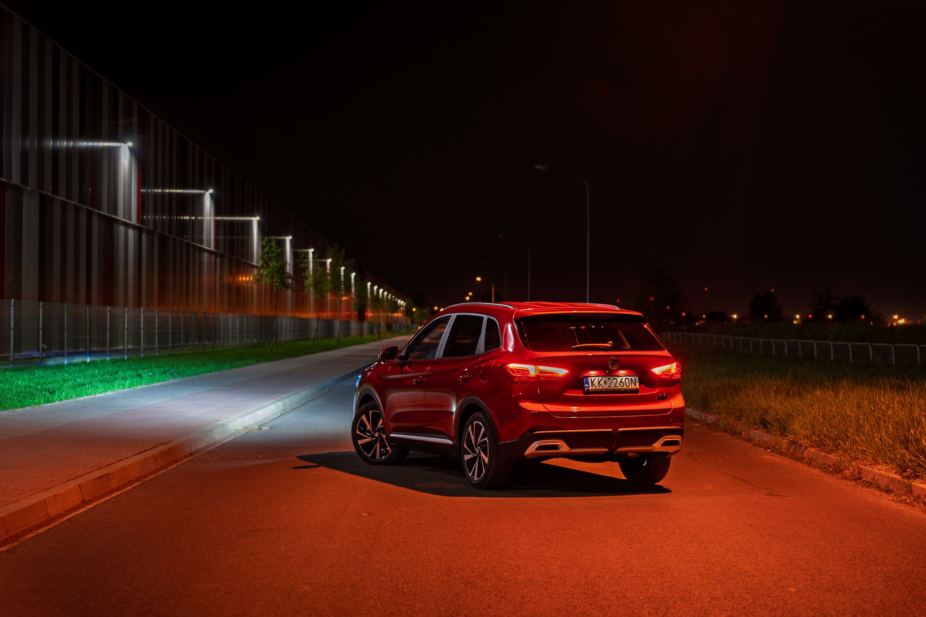 Stylish red SUV parked on a road at night in Kokotów, Poland, with streetlights illuminating the scene.
