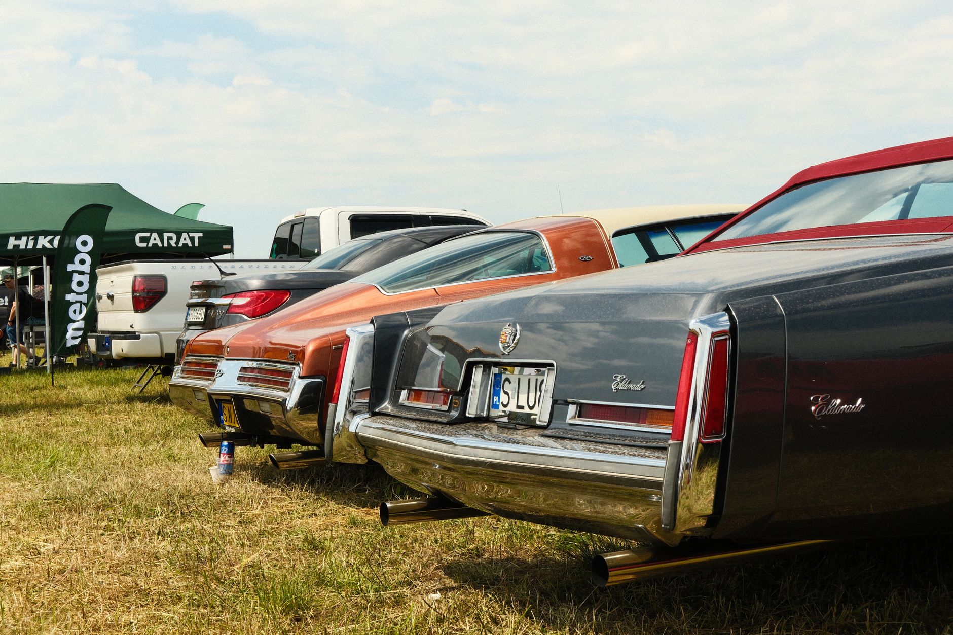 Vintage Cadillac cars lined up at an outdoor show in Katowice, showcasing automotive history.