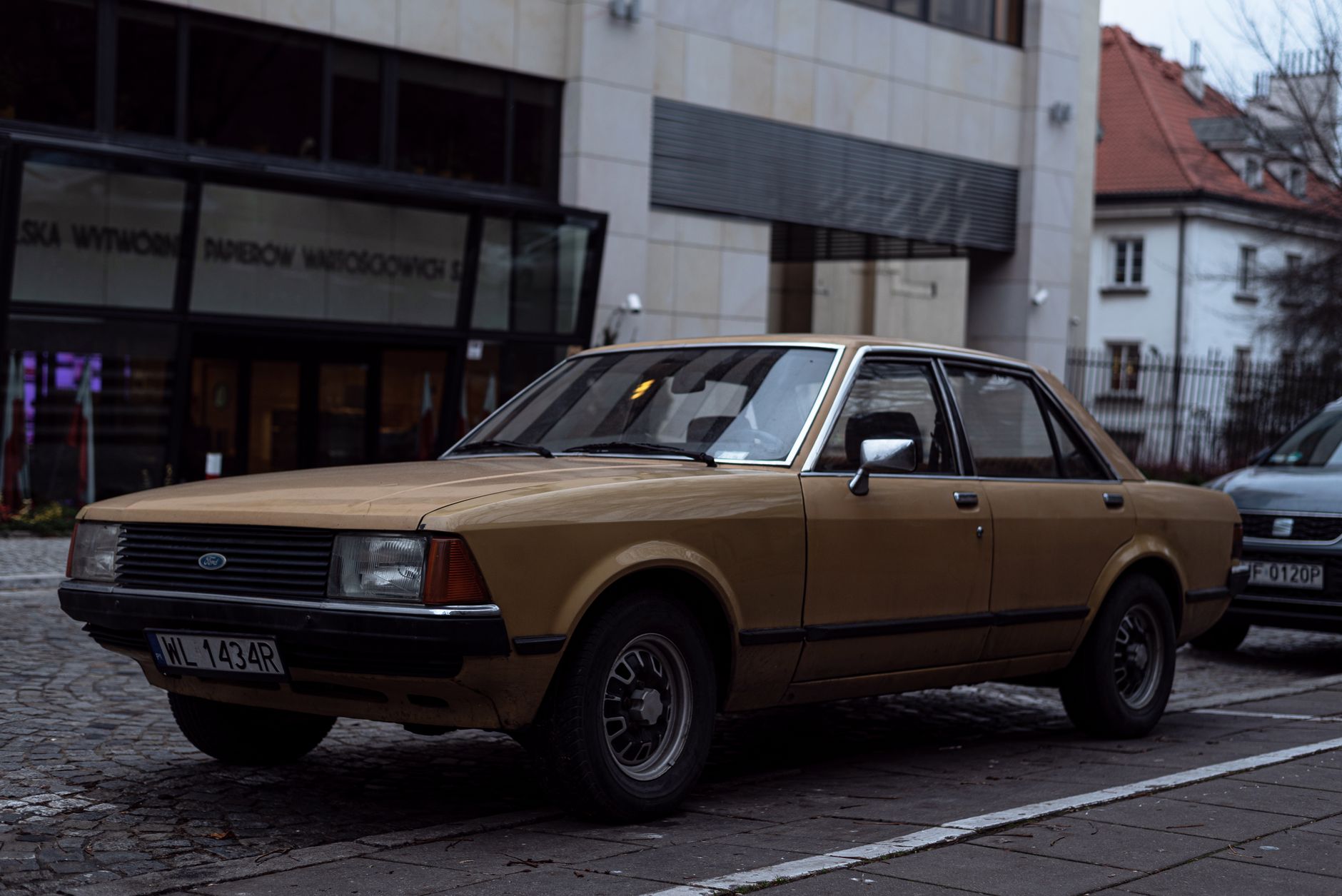 Classic vintage Ford car parked on city street with cobblestone paving.