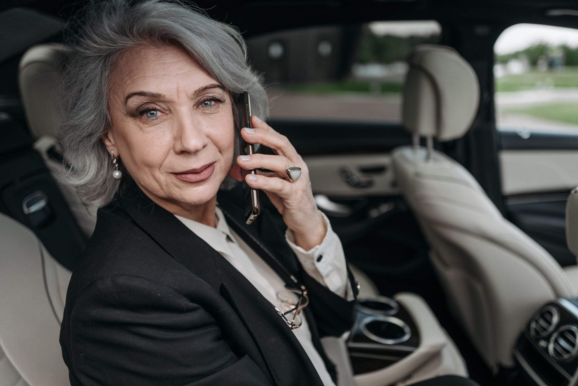 Elegant senior woman in luxury car speaking on smartphone, exuding confidence and professionalism.