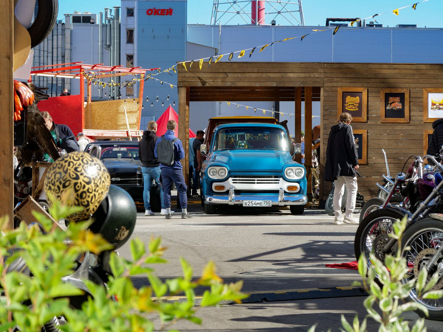 A vibrant auto show featuring vintage cars and motorcycles in an outdoor market setting.
