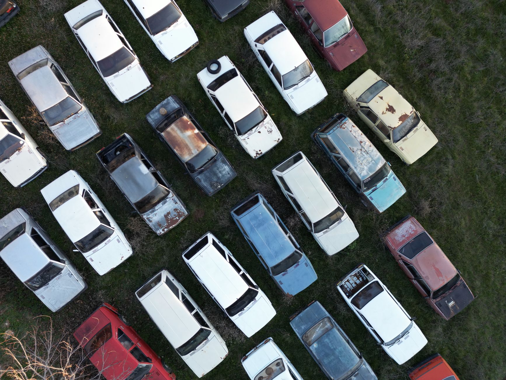 Aerial shot of vintage abandoned cars lined up in a field in Denizli, Türkiye.