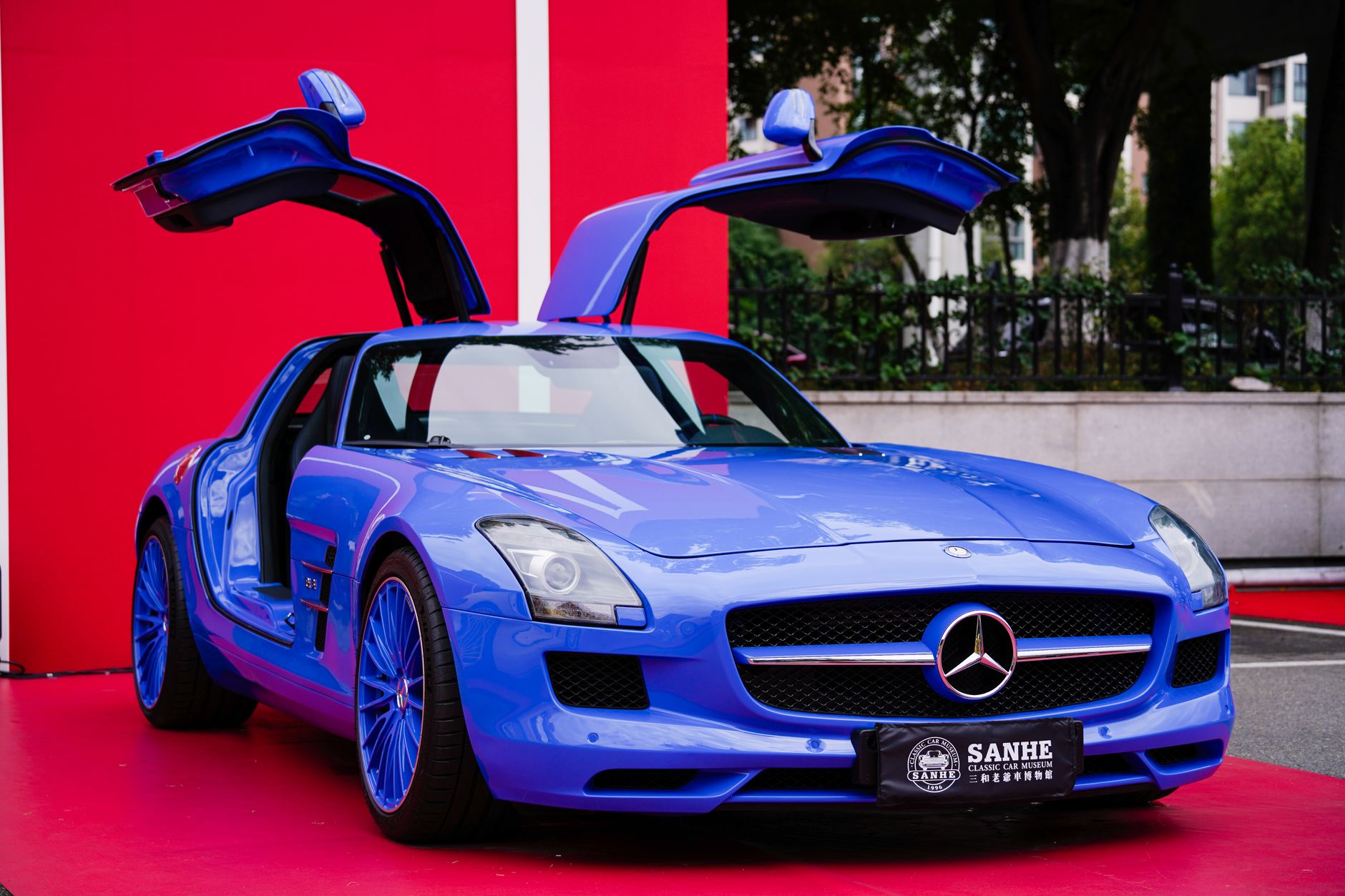 A sleek blue sports car featuring gullwing doors on display outdoors.