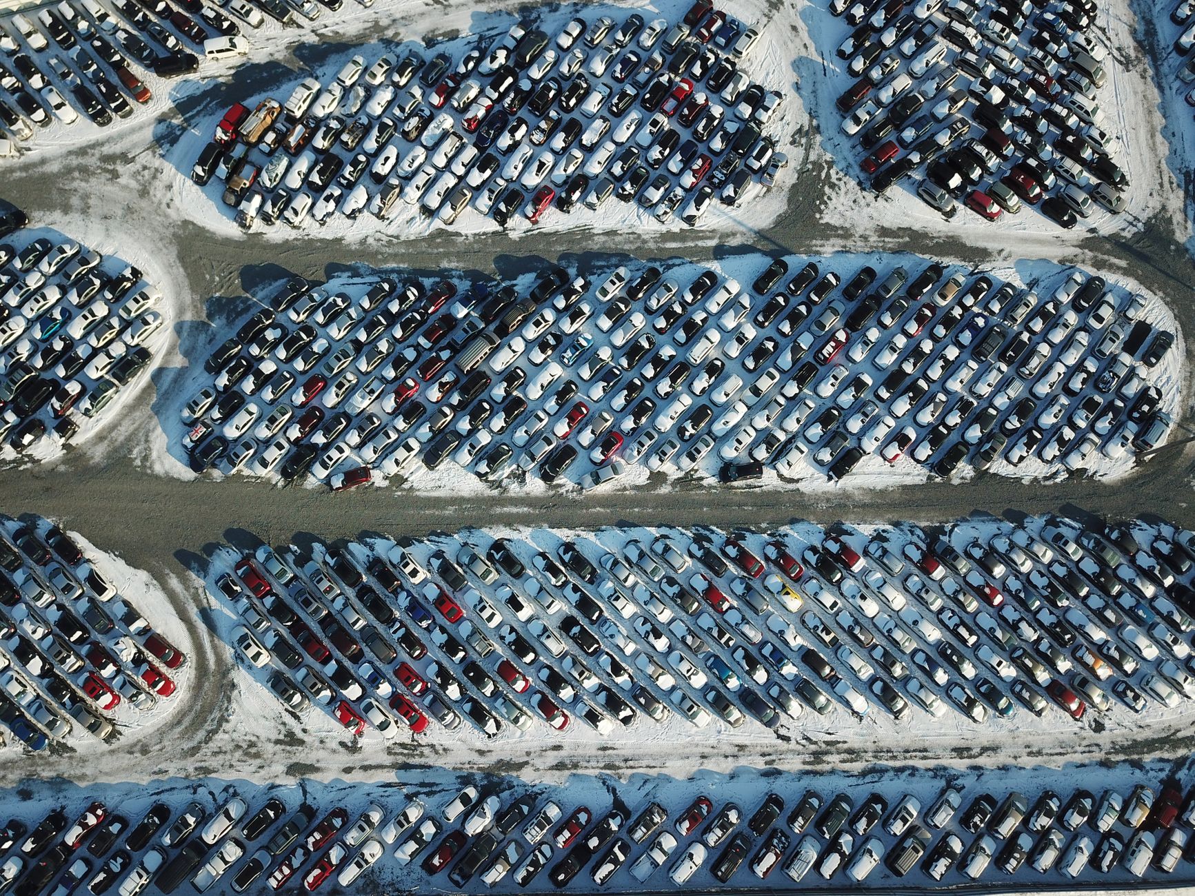 Aerial shot of cars parked in a snow-covered lot, showcasing an organized layout during winter.