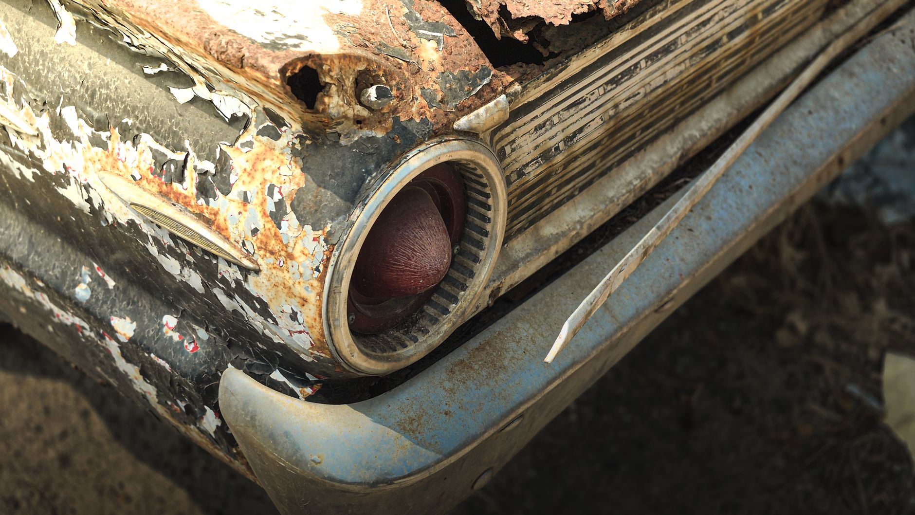 Detailed view of a deteriorating vintage car with rust and peeling paint.